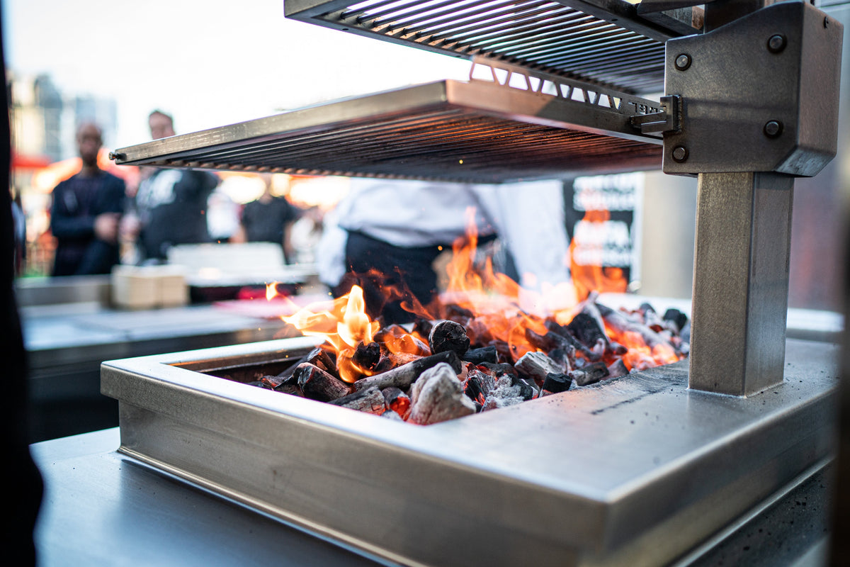 Josper open charcoal grill in service, grate raised above the burning charcoal bed